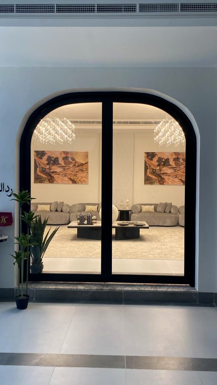 Wide arched black framed glass entrance to a living room