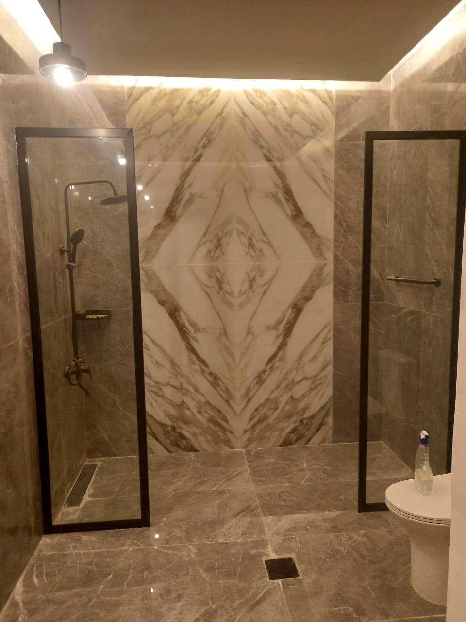 Dark marble bathroom with shower and illuminated ceiling detail