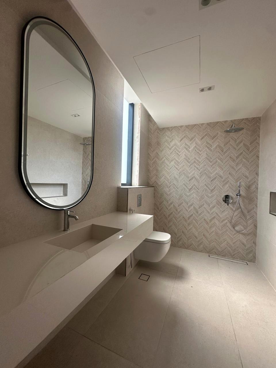 Light stone bathroom with long vanity and arched mirror