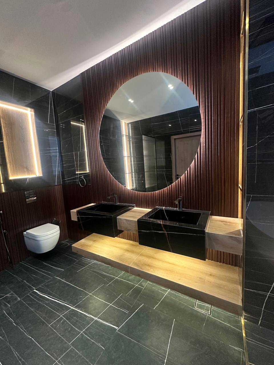 Bathroom with round illuminated mirror and timber vanity