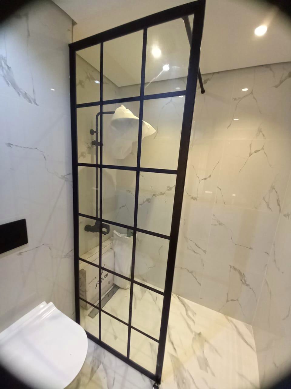 Black grid framed shower enclosure in a marble bathroom